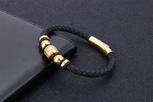 Macro shot of black braided leather bracelet with gold beads and magnetic clasp detail