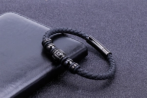Close-up of a black braided leather bracelet with magnetic metal clasp on a leather wallet