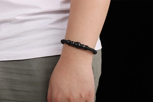 Close-up of men's braided black leather bracelet with black beads on a male model