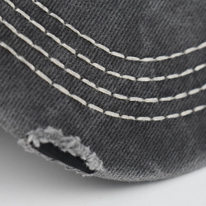 Dettaglio macro del berretto in cotone grigio scuro con cuciture bianche e bordi consumati effetto
