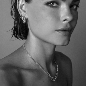Close-up of double layer silver chain necklace and matching hoop earrings on a model