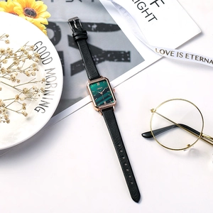 Vue à plat d'une montre vintage avec cadran en marbre vert, boîtier or rose et cuir noir