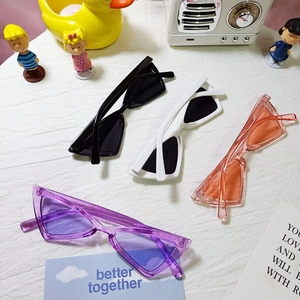 Flat lay of colorful triangle cat-eye sunglasses for kids with diverse playful props