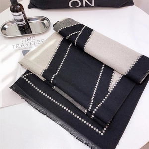 Detail view of monochrome geometric diamond knit scarf with fringe on a minimal tabletop