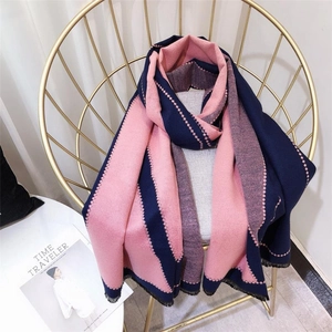 Detail view of pink and navy colorblock scarf with tassel fringe on a gold chair