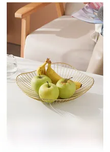 Nahaufnahme eines goldenen Obstkorbs mit Wellenrand, gefüllt mit frischen Äpfeln und Bananen