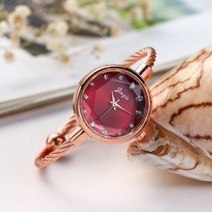 Detail of rose gold cable bracelet watch with red geometric faceted crystal dial