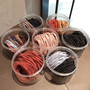 Macro view of seven jars filled with colorful elastic hair bands on a leather surface