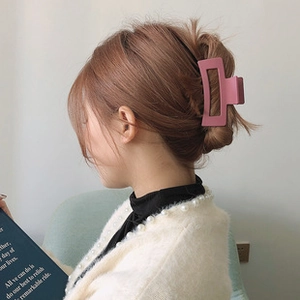Detail of matte dusty pink rectangular hollow hair claw clip worn on hair for styling