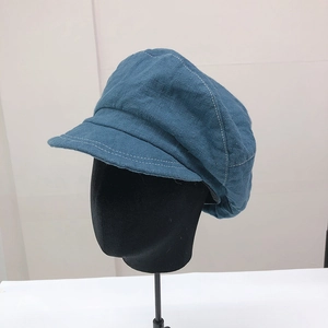 Dettaglio del cappello newsboy blu scuro con cuciture bianche a contrasto e pannelli