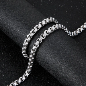 Collier chaîne à mailles carrées en acier inoxydable argenté sur fond sombre