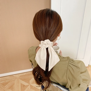 Cream bow hair scrunchie shown from a back view on a model with long hair tie accessory