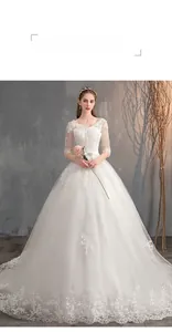 Dettaglio dell'abito da sposa bianco a spalle scoperte con maniche lunghe e pizzo delicato