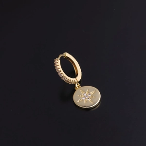 Detail of gold huggie hoop earring with starburst pendant and sparkling cubic zirconia