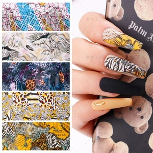 Detail showing animal print and vintage text nail stickers on long matte nails