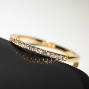 Macro detail of a gold minimalist ring with micro-pave cubic zirconia on black base