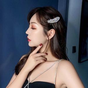 Elegant silver feather hair clip with sparkling rhinestones worn by a fashion model