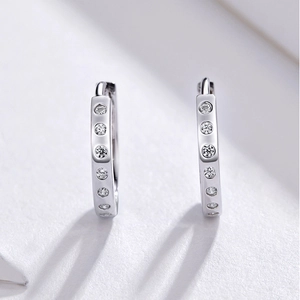 Close-up of polished silver hoop earrings with six vertical sparkling clear zircons