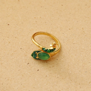 Detailed view of golden peacock ring with green gemstone and enamel feather textures