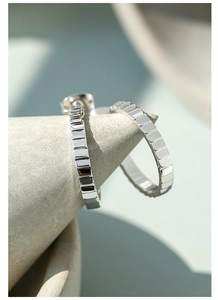 Detail shot of silver earrings featuring a textured geometric pattern and metallic finish