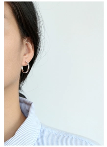 Close-up of textured silver hoop earrings with 925 silver needle on model
