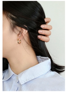 Classic small golden hoop earrings shown on model with blue striped shirt