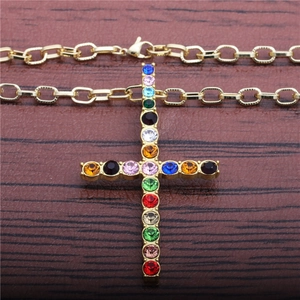 Golden Cuban link chain with a colorful rhinestone inlaid cross pendant on wood background