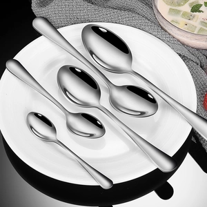 Set of minimalist stainless steel spoons in various sizes on a white decorative plate