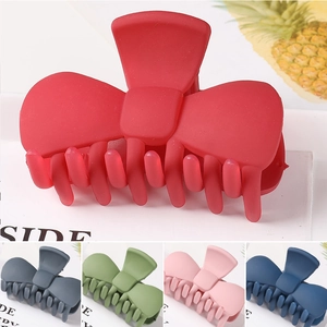 Detail view of large matte metal hair claws in five colors with bow-knot design