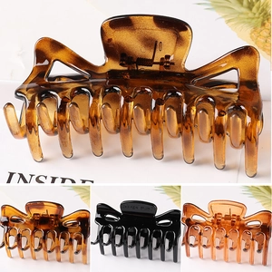 Detailed view of large resin hair claws in tortoiseshell amber, black, and brown colors