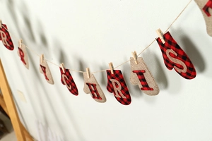 Close-up of rustic Merry Christmas bunting with red plaid mittens and wooden clips