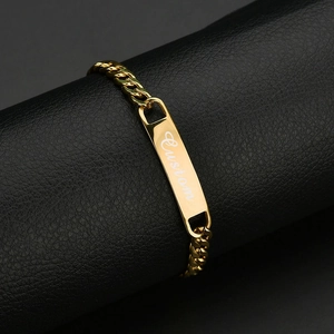 Close-up of gold Cuban link bracelet featuring a custom engraved identification plate