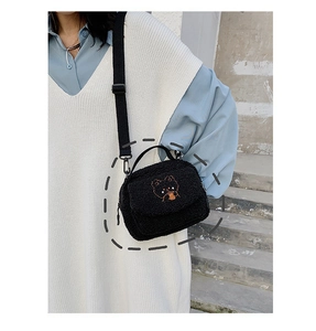 Close-up of black fuzzy crossbody bag featuring a cute brown cartoon bear embroidery
