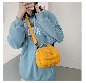 Detail of yellow plush crossbody bag with bear embroidery and adjustable shoulder strap