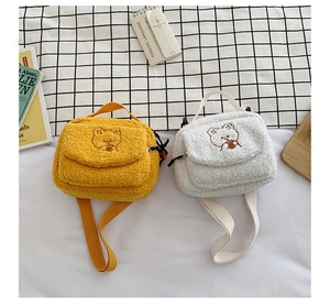 Detail of white and yellow plush crossbody bags with cute embroidered bear patterns