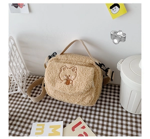 Detail of khaki plush crossbody bag featuring cute bear embroidery and dual handles