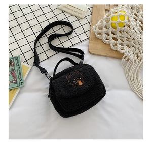 Detailed view of black plush crossbody bag featuring cute bear embroidery on fuzzy fabric