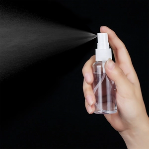 Action shot of 50ml clear PET spray bottle releasing fine mist against a dark background