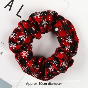 Close-up of red and black checkered scrunchie with white snowflake patterns and 10cm diameter