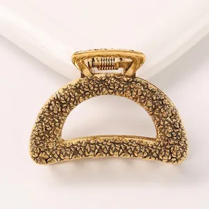 Detail of golden alloy claw clip featuring unique molten lava texture and metallic finish