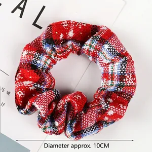Detail of a 10cm red plaid scrunchie featuring festive white snowflake patterns