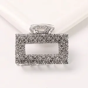 Detail view of rectangular hollow metal hair claw clip with crushed silver texture finish