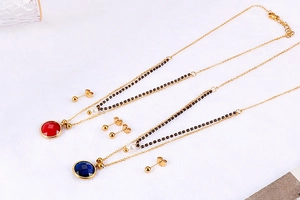 Detail of gold double-layer necklaces with red and blue gemstone pendants and matching earrings