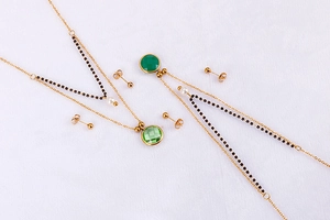 Detail view of gold titanium necklaces with green gemstones and elegant pearl earrings set
