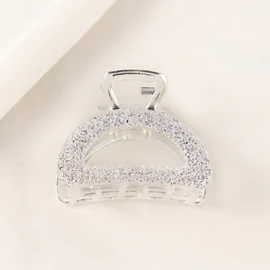 Close-up of silver semi-circle hair claw clip with detailed floral texture and metallic finish