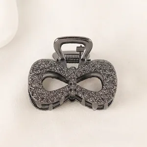 Macro detail of dark grey bow hair claw clip with intricate rose flower embossment