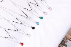 Close-up of colorful circular glass pendants on silver stainless steel necklace sets