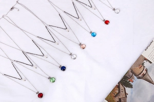 Detailed display of colorful glass pendant necklaces in silver-toned stainless steel