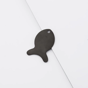 Macro detail of a black fish-shaped stainless steel pendant with a smooth mirror finish