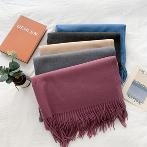 Soft cashmere-feel scarves with tassels in five candy colors stacked on white fabric